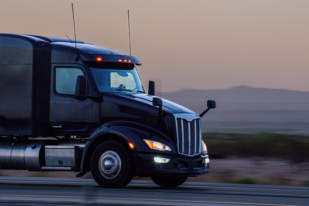 A Black Semi Truck and Trailer Traveling East on Highway 10 a few Miles East of El Paso Texas Just After Sunset